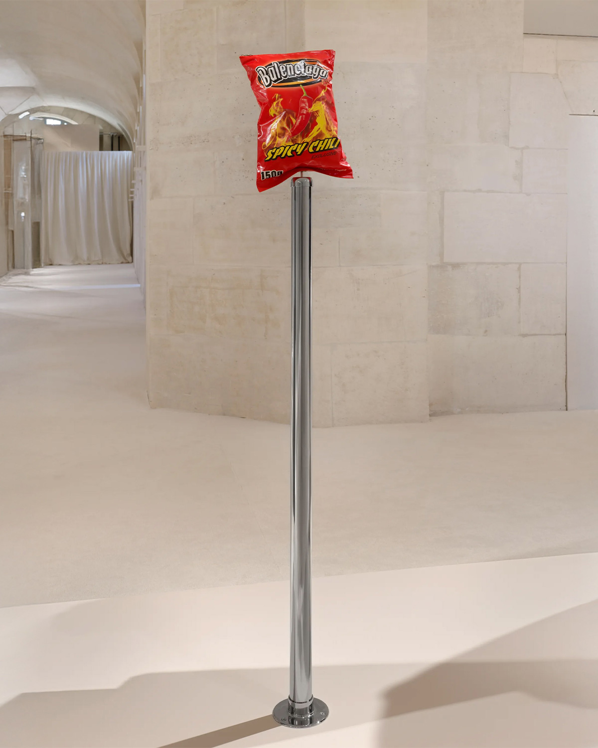 A Balenciaga chip-bag pouch displayed on a stainless steel stanchion by Andrew J. Greene | Source: Balenciaga